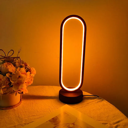 Luminária de mesa LED com anel de luz acesa sobre mesa com flores