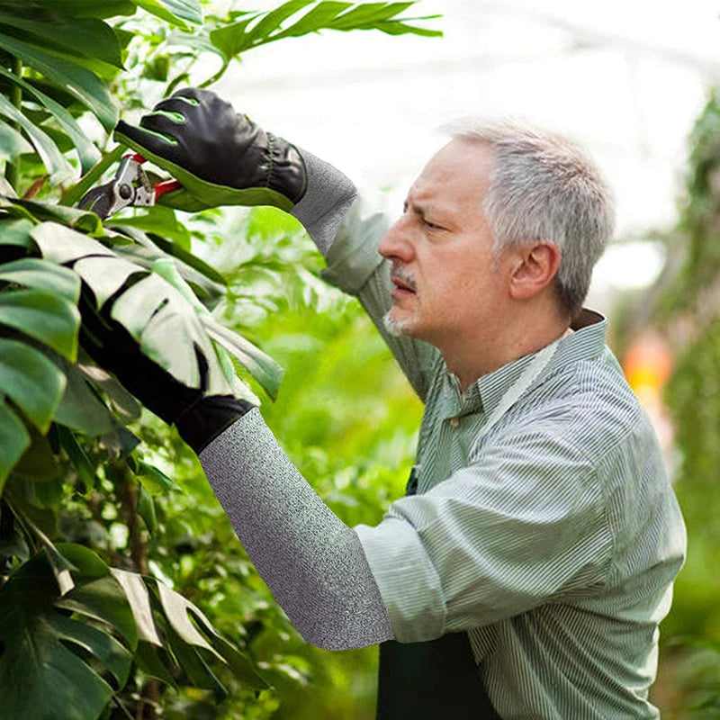 Homem usando manga de proteção anticorte durante poda de plantas